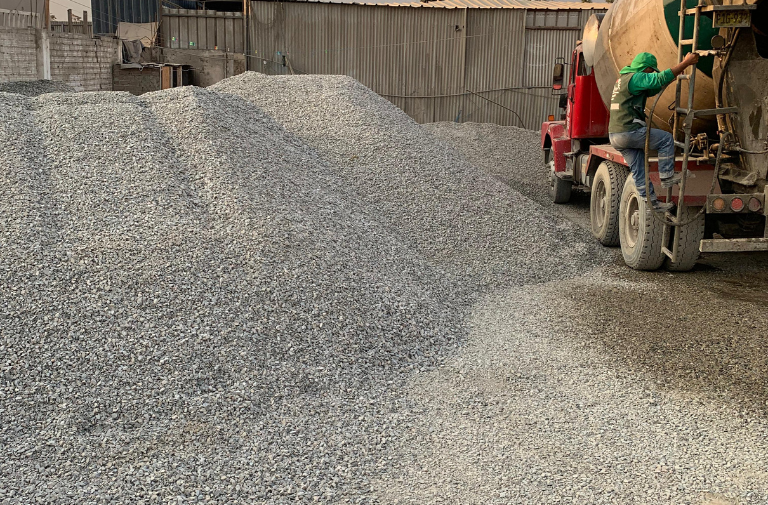 Pila de piedra chancada con un camión mixer al fondo
